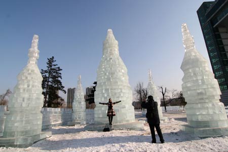 A visitor poses for pictures among the tower-style ice sculptures at the Century Square in Jilin city, northeast China's Jilin Province, Dec. 21, 2008. An ice lantern show will be held in Jilin city on Dec. 23, 2008.