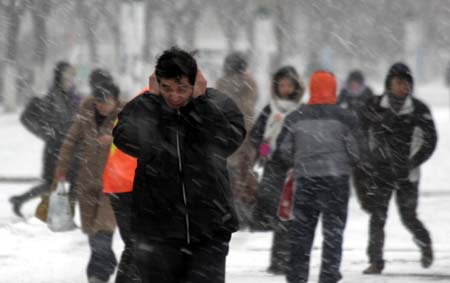 Citizens walk on a snow-covered road in Weihai, east China's Shandong Province, Dec. 22, 2008. Due to the continuous snowfall, the expressway from Qingdao to Weihai was blocked and passenger coaches set out from Weihai were cancelled on Monday.