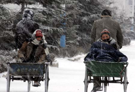 People ride tricycles on a snow-covered road in Weihai, east China's Shandong Province, Dec. 22, 2008. Due to the continuous snowfall, the expressway from Qingdao to Weihai was blocked and passenger coaches set out from Weihai were cancelled on Monday.