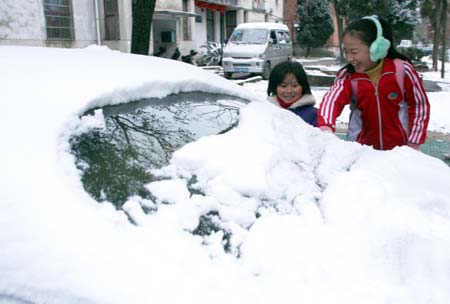 Students touch snow piling on a car on their way to school in Sizhou County of Dexing, east China's Jiangxi Province, Dec. 22, 2008. The first snow of this winter fell in Dexing this morning and dropped the temperature below zero degree Celsius.