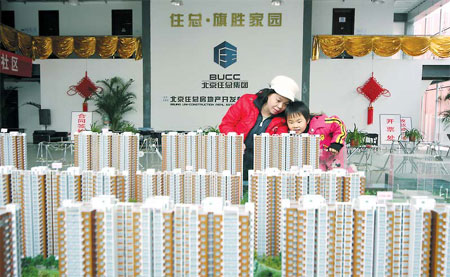 Would-be buyers look at the model of a new housing project in Beijing. [China Daily]