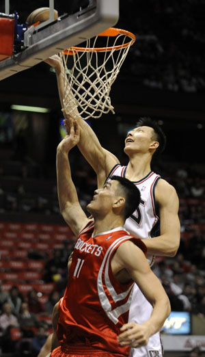 New Jersey Nets forward Yi Jianlian tips in a shot over Houston Rockets center Yao Ming in the first quarter of their NBA basketball game in East Rutherford, New Jersey, December 22, 2008.