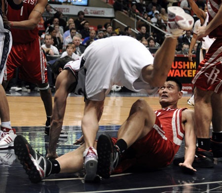 Houston Rockets center Yao Ming falls down after New Jersey Nets forward Eduardo Najera (top) committed an offensive foul by trying to drive into him while shooting in the second quarter of their NBA basketball game in East Rutherford, New Jersey December 22, 2008.