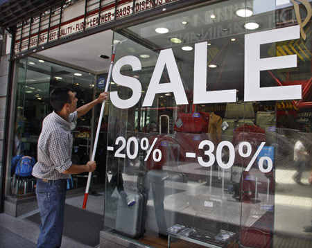 A shop assistant cleans a window at a clothing store which is offering sale discounts in Buenos Aires, Dec. 15, 2008. The world's economies limped toward Christmas on Tuesday, with a U.S. contraction confirmed, Britain shrinking more sharply than thought and Spain and New Zealand languishing in recession.[Xinhua]