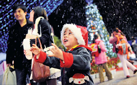 A boy revels in artificial snow at a shopping mall in Xiamen, Fujian province, as people in the coastal city celebrated Christmas Eve yesterday. [Yang Ge/China Daily] 