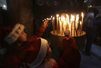 Palestinian children light candles in the Church of the Nativity in the West Bank town of Bethlehem December 24, 2008, before the annual Christmas procession.