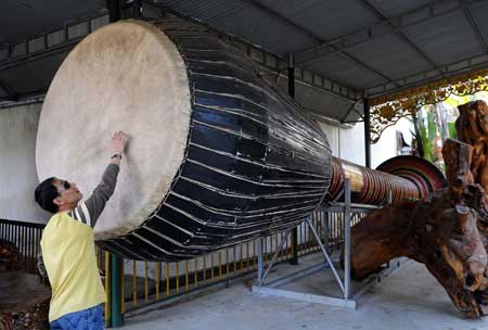 A tourists beats a huge Xiangjiao Drum, a popular musical instrument of China's Dai ethnic group, at a scenic spot in Luxi City, Dehong Dai and Jingpo Autonomous Prefecture, southwest China's Yunnan Province, on Dec. 23, 2008. Hundreds of precious and rare stones, fossils and root sculptures were displayed in the scenic spot named 'Mengbanaxi Rarity Garden', attracting numerous tourists from home and abroad. 