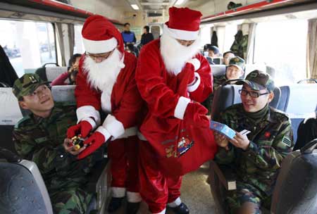 Train crew wearing Santa Claus outfits give presents to passengers during a photo call as a part of Christmas event at a train in Jecheon, about 168 km (104 miles) southeast of Seoul, Dec. 23, 2008. 
