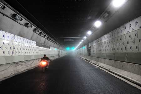 A man drives a motorcycle in a newly completed tunnel under the Yangtze river in Wuhan, capital of central China's Hubei Province, Dec. 24, 2008. 