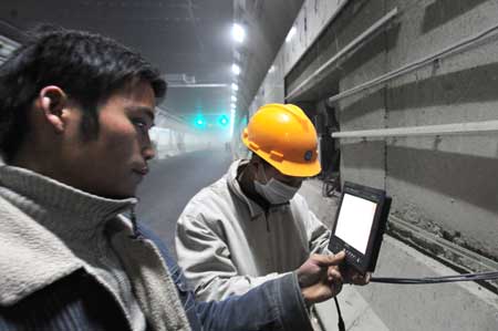 Two technicians check the vedio observation system in a newly completed tunnel under the Yangtze river in Wuhan, capital of central China's Hubei Province, Dec. 24, 2008. 