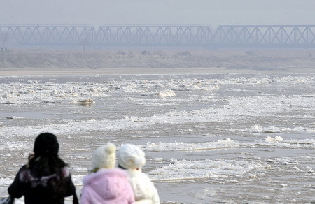 People watch ice and slush floating on the Yellow River at the Jinan section in Jinan, east China's Shandong Province December 23, 2008. Strong cold fronts have hit most areas of China these days, bringing temperatures down 6-12 degrees Celsius. [Xinhua]