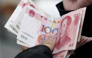 A customer holds renminbi banknotes at an ATM in a bank in Beijing, Nov 26, 2008.The yuan will be used in transactions with neighboring trade partners as part of a pilot project - in what could be the first step on the road to making it an international currency. [Xinhua]