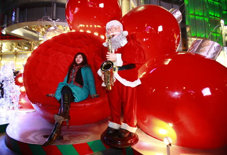 A Chinese girl sits with Santa Claus in downtown Beijing Dec. 24, 2008. [Li Mingfang/Xinhua]