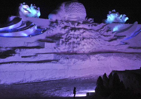 A visitor stands in front of a giant Santa Claus ice sculpture for the upcoming 25th Harbin International Ice and Snow Festival at a park in Harbin, Heilongjiang province, December 24, 2008. China's freezing northern city of Harbin is building what organizers say is the world's largest Santa Claus ice sculpture.[Xinhua/Reuters]