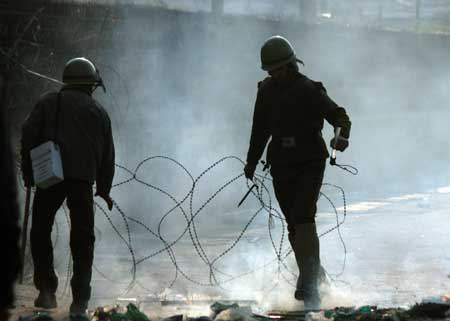 Indian paramilitary soldiers lay wires to block a road for preventing protests in Srinagar, summer capital of Indian controlled Kashmir, Dec. 26, 2008. Government forces on Friday clashed with hundreds of rock-throwing protesters.