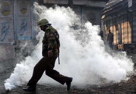 An Indian police kicks a teargas away during a protest in Srinagar, summer capital of Indian controlled Kashmir, Dec. 26, 2008. 