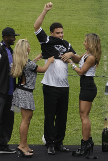 Brazilian striker Ronaldo is helped by models to put on a Corinthians club jersey in Sao Paulo December 12, 2008.