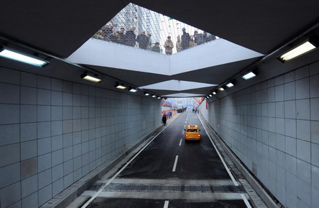 Local residents gather at an exit of a tunnel that runs beneath the Yangtze River as a car moves through it in Wuhan, central China's Hubei province, December 28, 2008. [Xinhua]