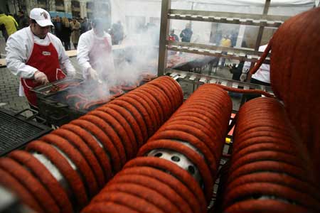 Men grill part of a sausage looped around a rack in Bucharest during a Guinness World Record event for the world's longest sausage Dec. 27, 2008. The sausage measured 392 meters (1286 feet) and set a new world record.[Xinhua/Reuters]