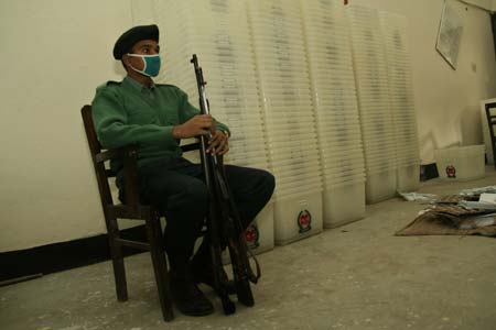 A policeman sits next to election ballot boxes to be distributed to the polls centers in Dhaka, capital of Bangladesh, on Dec. 28, 2008. Bengalese are counting down hours of the ninth parliamentary elections that is scheduled to be held on Dec. 29, 2008. [Qamruzzaman/Xinhua]