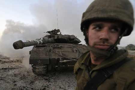 An Israeli soldier stands in front of a tank just outside the northern Gaza Strip December 28, 2008. [Xinhua/Reuters]