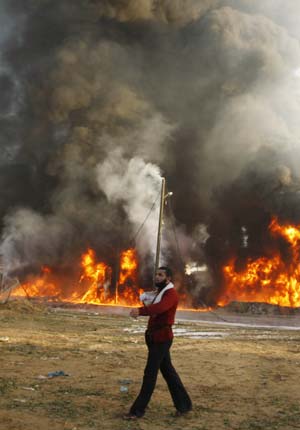 A Palestinian man walks past a fire following an Israel air strike in Gaza Strip December 28, 2008. Israel launched air strikes on Gaza for a second successive day on Sunday, piling pressure on Hamas after 285 people were killed in one of the bloodiest 24 hours for Palestinians in 60 years of conflict with the Jewish state.[Xinhua/Reuters]