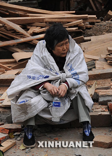  5月13日，四川省北川县地震灾区一位老人坐在路旁等待救助。 记者从四川省绵阳市抗震救灾指挥部了解到，受灾特别严重的北川县老县城80%、新县城60%以上建筑物垮塌，县城周边发生大面积山体滑坡。 另据了解，北川县城所属曲山镇共2万余人，其中城区1万余人，仅4000多人脱险，其余人员下落不明。
