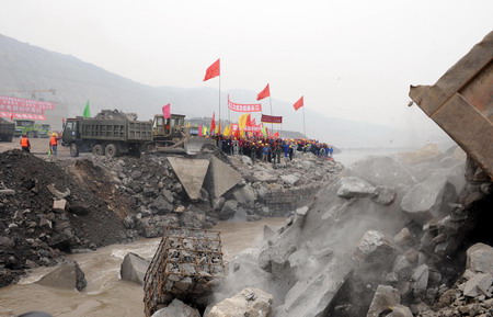Workers empty out trucks loaded with rocks and stones to block the Jinsha River at Xiangjiaba, bordering Shuifu County of Yunnan province and Yibin County of Sichuan province, southwest China December 28, 2008. The third largest hydropower plant in China, which is expected to be completed by 2015, will be able to generate 30.7 billion kw hours of electricity a year.[Xinhua]