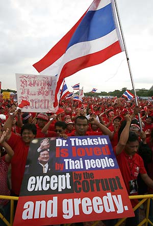 Supporters of former Prime Minister Thaksin Shinawatra wave a Thai flag and hold a banner during a protest against the Government in Bangkok, December 28, 2008.[Xinhua/Reuters] 