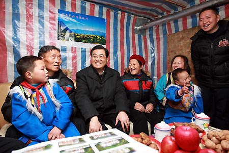Chinese President Hu Jintao (3rd L) smiles as he talks with family members of Ma Xizhi (2nd L) at Caijiagang Village of Xuankou Township in Wenchuan County, southwest China's Sichuan Province, Dec. 29, 2008.