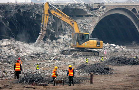 An earth-moving excavator is busy with the backout project of scraping down the new Lugou Bridge, which is parallel to the adjacent historical Lugou Bridge (Marco Polo Bridge), at the suburb of Beijing, Dec. 28, 2008. [Wu Changqing/Xinhua]