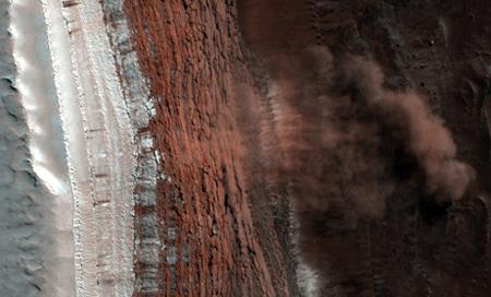 Snapped by the Mars-orbiting HiRISE camera, billowing clouds of dust revealed the first-ever picture of active landslides occurring on Mars at the base of a towering slope near the planet's north pole in March. [Photo: NASA]