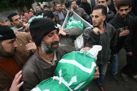 A Palestinian mourner carries the body of 4-year-old Dena Balosha (front), one of five members of the same family including three children and two teenagers who were killed in an Israeli missile strike, during their funeral in the Jebaliya refugee camp, in Gaza Strip, Dec. 29, 2008. [Xinhua]