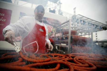 A man grills part of a sausage looped around a rack in Bucharest during a Guinness World Record event for the world's longest sausage Dec. 27, 2008. The sausage measured 392 meters (1286 feet) and set a new world record. 