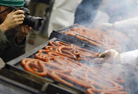 A photographer takes pictures of a grilled sausage looped around a rack in Bucharest during a Guinness World Record event for the world's longest sausage Dec. 27, 2008.