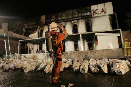 A Thai fire official takes a picture of the bodies of victims outside Santika nightclub in Bangkok January 1, 2009. A blaze at the top Bangkok nightclub killed at least 59 people celebrating the New Year on Thursday and injured many others, local media reported. [Xinhua/Reuters]