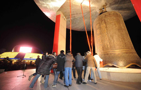 People strike a giant bell at the China Millennium Monument to celebrate the New Year in Beijing, January 1, 2009. [Xinhua]