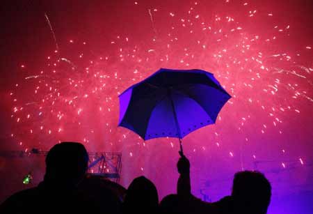 Spectators watch a fireworks display amidst the rain during a New Year's eve countdown in Fort Bonifacio, Metro Manila January 1, 2009. 