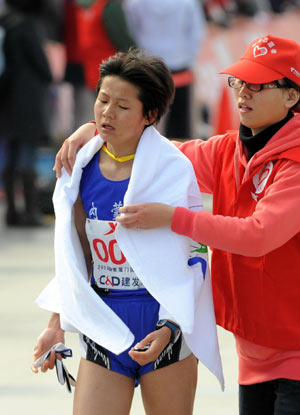 China&apos;s Zhang Yingying is helped by a volunteer after reaching the finish line during the 2009 Xiamen International Marathon in Xiamen, southeast China&apos;s Fujian Province, Jan. 3, 2009. Zhang won the second place of women&apos;s race with 2 hours 32 minutes and 57 seconds. 