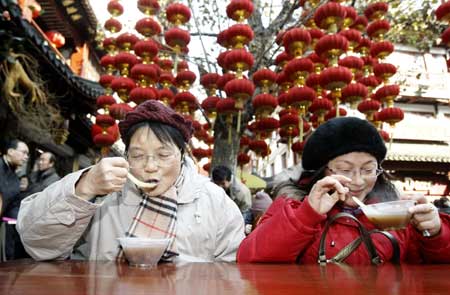 Citizens take free 'Laba Porridge' outside a time-honored pharmacy in Shanghai, China, Jan. 3, 2009. Caldrons of 'Laba Porridge', which is made from dozens of ingredients, were served freely for local citizens by a pharmacy in Chenghuang Temple in Shanghai on the Laba Festival on Saturday. 