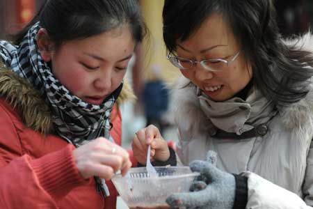 Two citizens enjoy Laba porridge at Pilu Temple in Nanjing, capital of east China's Jiangsu Province, on Jan. 3, 2009. 