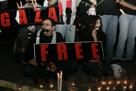 Protesters light candles and hold up signs that read 