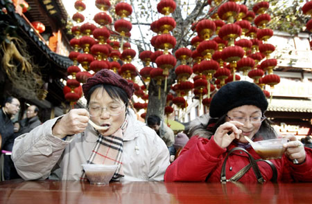 Two women eat free Laba porridge provided by a temple in Shanghai, January 3, 2009. Laba, often regarded as the start of celebrations for the Chinese lunar New Year, falls on the eighth day of the 12th lunar month. Eating porridge on Laba is believed to bring good fortune in the New Year. [Xinhua]