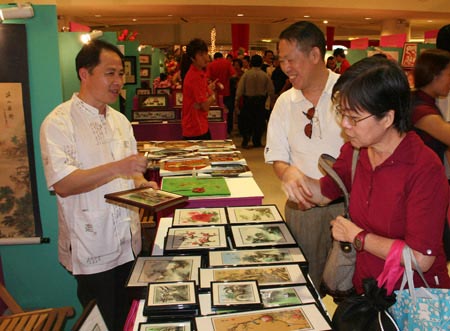 Visitors acquaint themselves with Chinese artworks during the Chinese Culture and Travel exhibition in Singapore, on Jan. 2, 2009. 