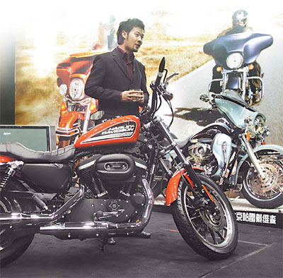 A man stands beside a Harley Davidson motocycle at the Top Essence Luxury Show in Beijing in late November. Over a third of the items in the show were reportedly displayed for the first time in Asia. [China Daily]