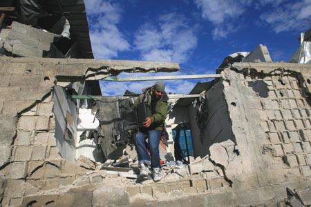 A Palestinian gets a TV set out of a destroyed house in Rafah refugee camp, southern Gaza Strip, Jan. 3, 2009. 