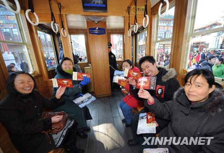 Visitors pose with tickets on a tram beginning trial operation in Qianmen Street, Beijing, Jan. 1, 2009.[Xinhua] 