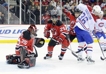 Montreal Canadiens winger Matt D'Agostini (36) backhands a shot off the mask of New Jersey Devils goalie Scott Clemmensen (35) in front of defenseman Johnny Oduya (29) in the first period of their NHL hockey game in Newark, New Jersey, January 2, 2009.[Xinhua/Reuters]