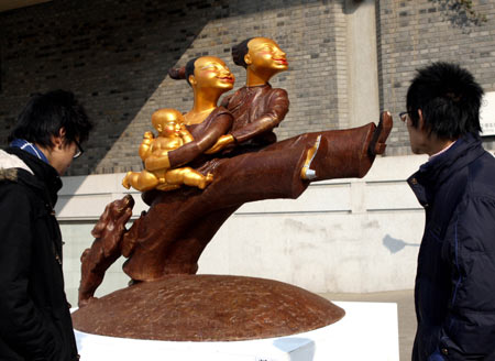 The visitors view a sculpture presented on the Fine Arts Exhibition of the Yangtze River Delta Region memorizing the 30th Anniversary of China's reforms and opening up campaign, in Hangzhou, capital of east China's Zhejiang Province, Jan. 3, 2009. [Cheng Ruixin/Xinhua]