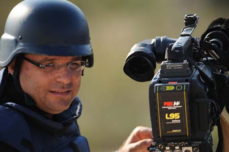 A journalist with helmet and bullet-proof vest films north Gaza Strip at the top of a hill near Gaza border, south Israel, Jan. 4, 2009. Hundreds of journalist and reporters from all over the world swarm into Israel and the west bank since Israel began the air strike to Gaza Strip on Dec. 27, 2008.[Yin Bogu/Xinhua]